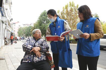 Census workers collect information from a woman in Lianyungang, in China's eastern Jiangsu province on November 1, 2020, as millions of census-takers began knocking on doors for a once-a-decade head count of the world's largest population that for the first time will use mobile apps to help crunch the massive numbers. (Photo by STR / AFP) / China OUT