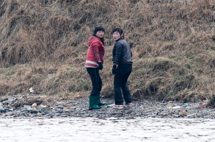 Dos mujeres norcoreanas en la orilla del río Yalu cerca de Sinuiju, frente a la ciudad china de Dandong (AFP PHOTO / Johannes EISELE)