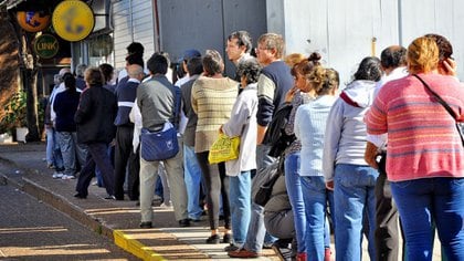 Beneficiarios de las ayudas estatales hacen fila frente a los bancos para percibir los subsidios de emergencia
