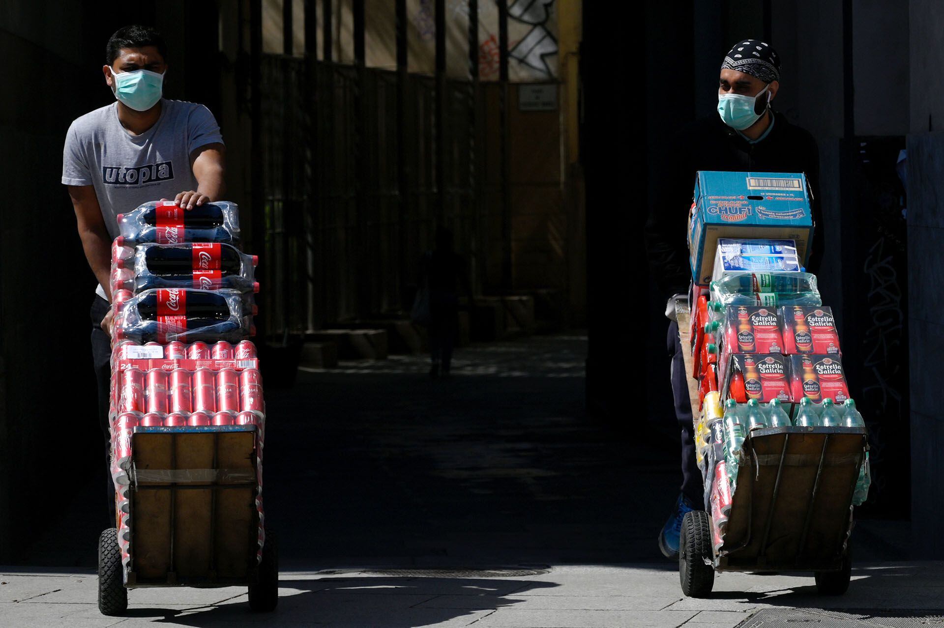 Dos proveedores de bebidas llevan su carga en una calle de Barcelona, España. 