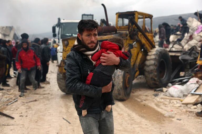  Un hombre carga el cuerpo de un niño que murió por el sismo en la localidad de Besnia, en la provincia de Idlib, Siria  