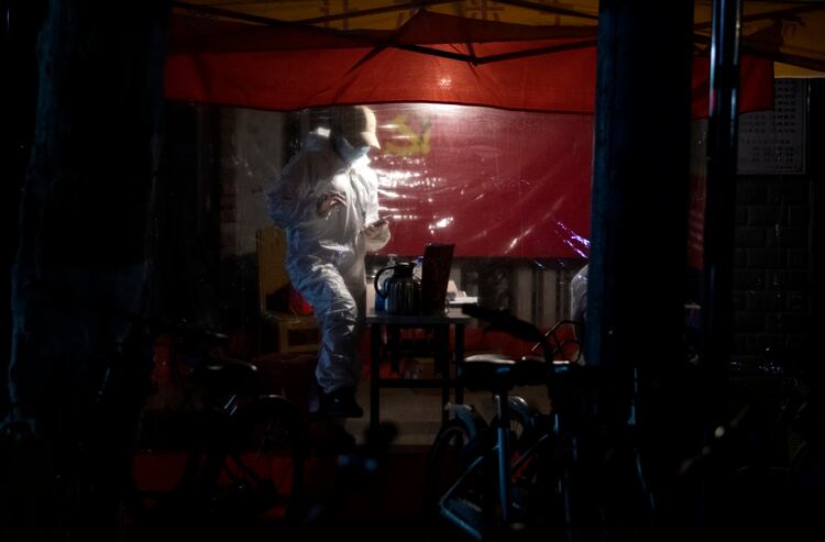 Un voluntario controla la entrada de un edificio en Wuhan (NOEL CELIS / AFP)