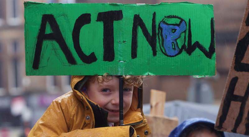 Un niño sostiene un cartel mientras la gente protesta durante la Conferencia de las Naciones Unidas sobre el Cambio Climático (COP26), en Glasgow, Escocia, Gran Bretaña. (REUTERS/Yves Herman)