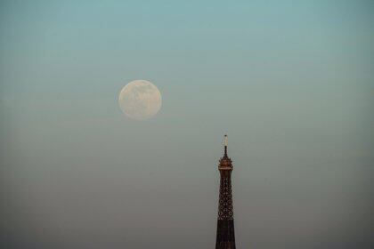La luna llena se eleva sobre la Torre Eiffel en París, el 26 de abril de 2021 (Photo by Martin BUREAU / AFP)