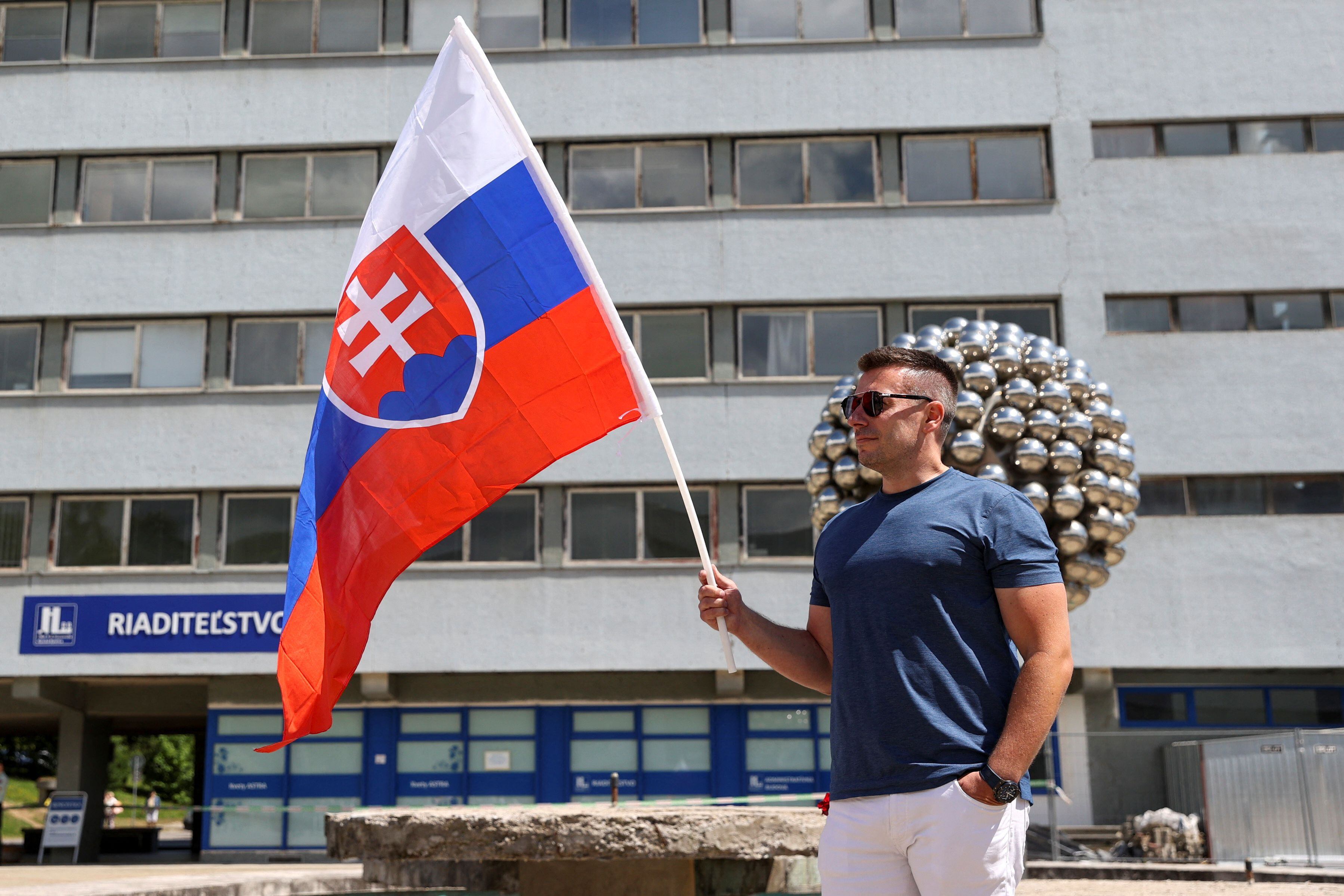 Un partidario sostiene una bandera de Eslovaquia cerca del F.D. Hospital Universitario Roosevelt, donde el primer ministro eslovaco Robert Fico está hospitalizado tras un intento de asesinato, en Banska Bystrica, (REUTERS/Bernadett Szabo)