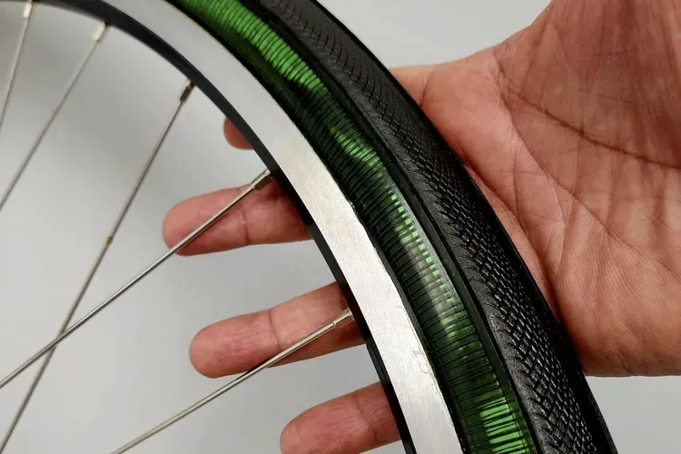 Un prototipo verde del neumático METL con la banda de rodadura aplicada. Es posible observar la bobina de NiTinol a través del neumático transparente. (The Smart Tire Company)