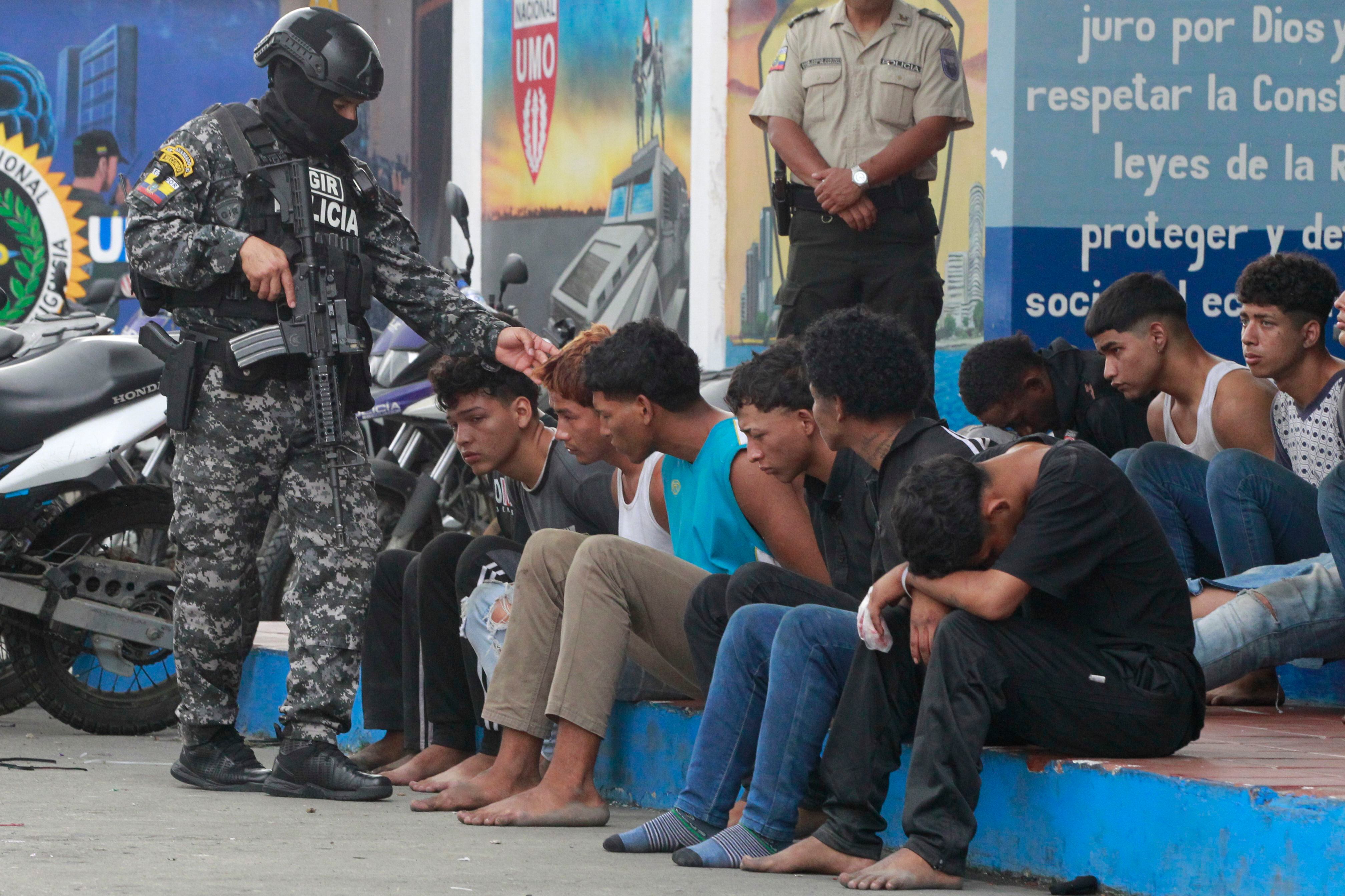 Un policía custodia a los detenidos de un grupo armado por la toma temporal de un canal de televisión en Guayaquil (Ecuador). EFE/Carlos Durán Araújo
