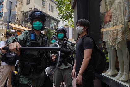 Policías antimotines forman una línea mientras identifican a peatones reunidos en el distrito Central de Hong Kong, el miércoles 27 de mayo de 2020. (AP Foto/Vincent Yu)