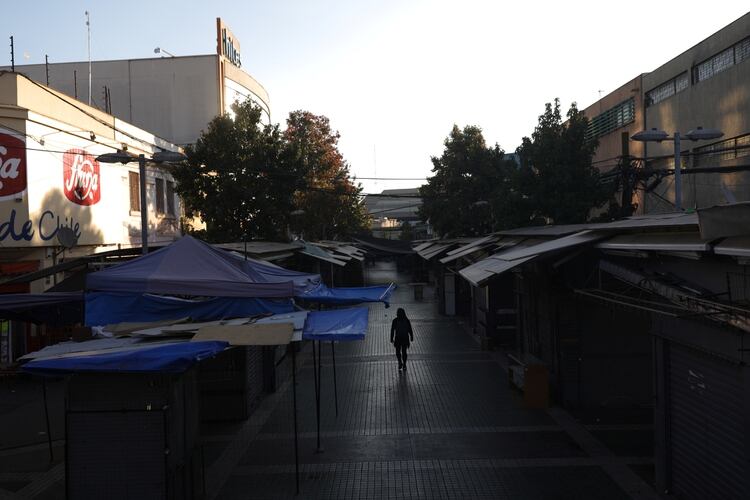 Una mujer camina por una calle rodeada de tiendas cerradas en un sector comercial en Santiago, durante la cuarentena por el brote de coronavirus (Reuters)