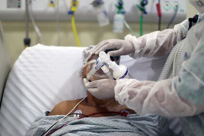 Un fisioterapeuta ajusta una máscara de oxígeno en un paciente con la enfermedad del coronavirus (COVID-19) en la UCI del Hospital Municipal de Parelheiros en Sao Paulo, Brasil 8 de abril de 2021.  REUTERS/Amanda Perobelli/File Photo