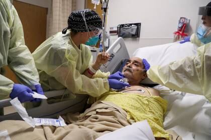 Anklesaria extrae un tubo de traqueotomía del paciente COVID-19 Vicente Arredondo, de 65 años.
