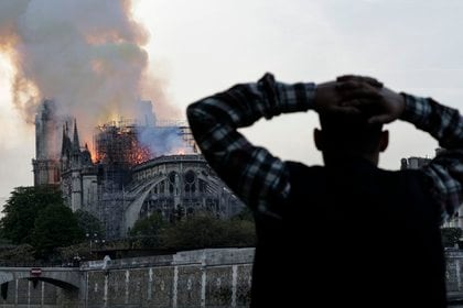 Un hombre observa arder la histórica catedral de Notre Dame, envuelta en llamas, en el centro de París el 15 de abril de 2019. (AFP)