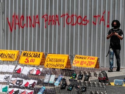 Un hombre camina junto a una pared en la que se lee la frase "vacuna para todos ya!" en Río de Janeiro. EFE/ Antonio Lacerda/ Archivo

