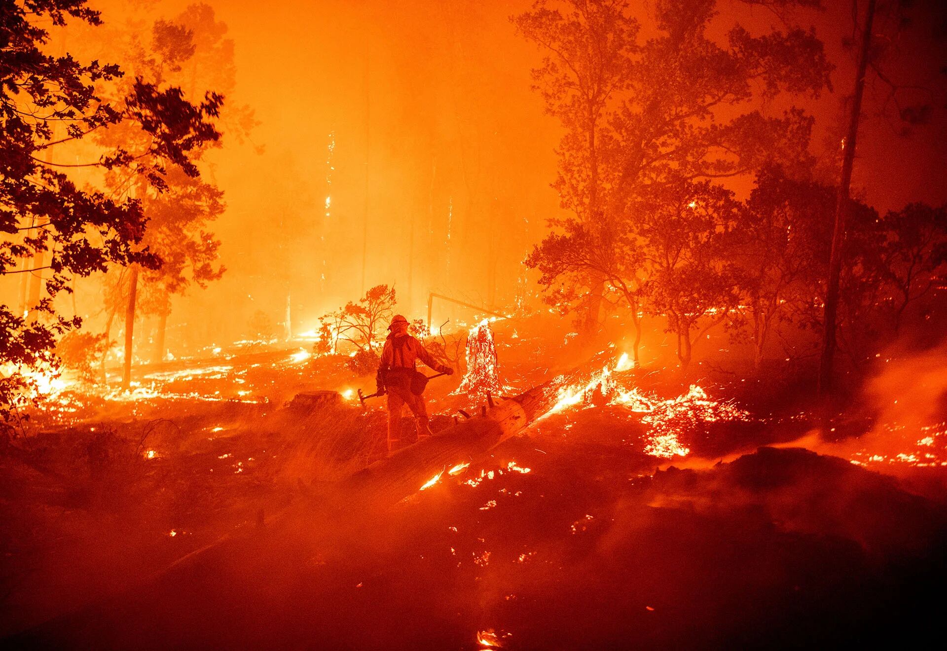 Un bombero trabaja para intentar sofocar el incendio mientras las llamas se dirigen hacia las casas en el área de Cascadel Woods de la zona no incorporada del condado de Madera, California, el 7 de septiembre de 2020 (Foto de JOSH EDELSON / AFP)