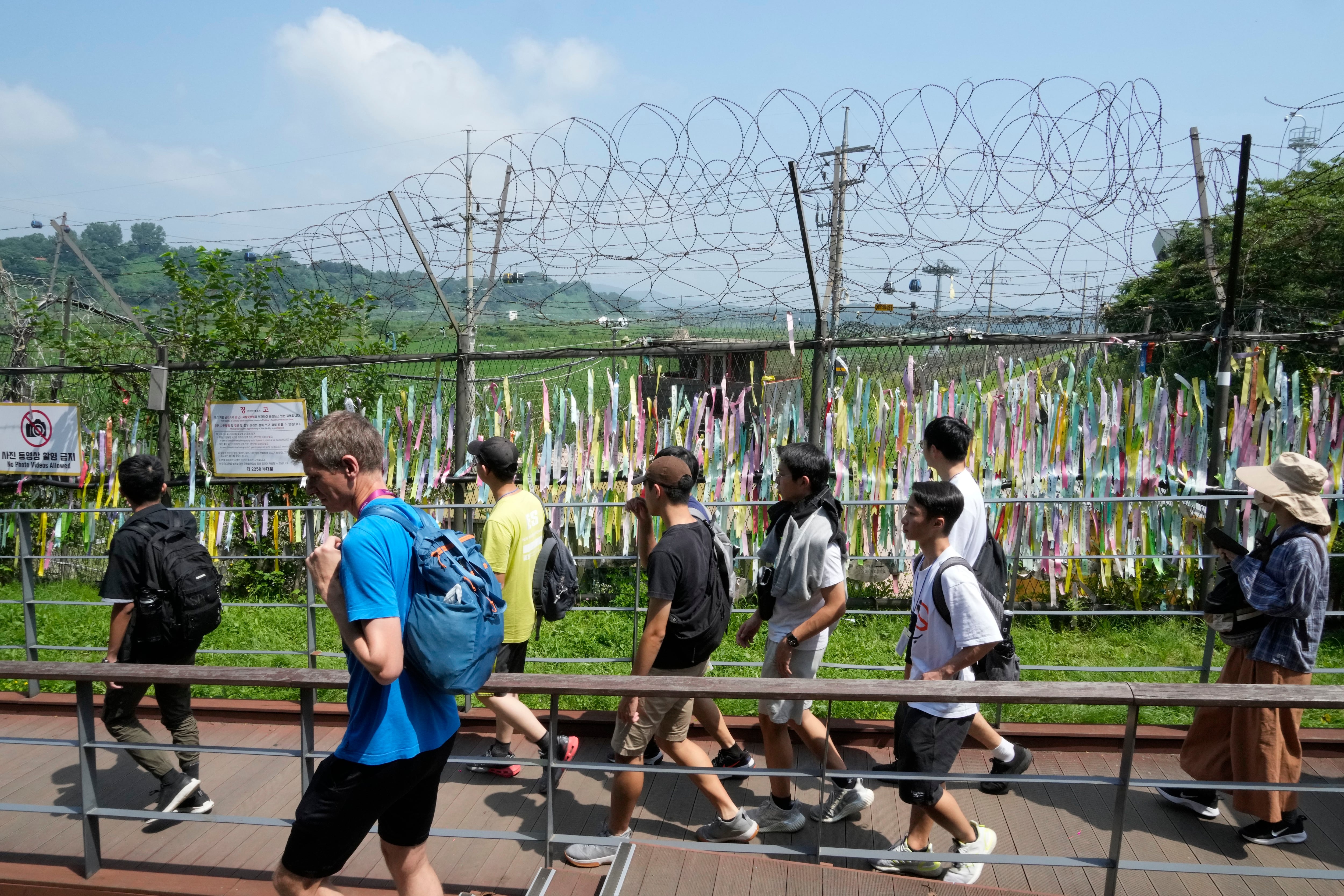 Los visitantes pasan por una cerca de alambre decorada con cintas escritas con mensajes que desean la reunificación de las dos Coreas  (AP Photo/Ahn Young-joon)