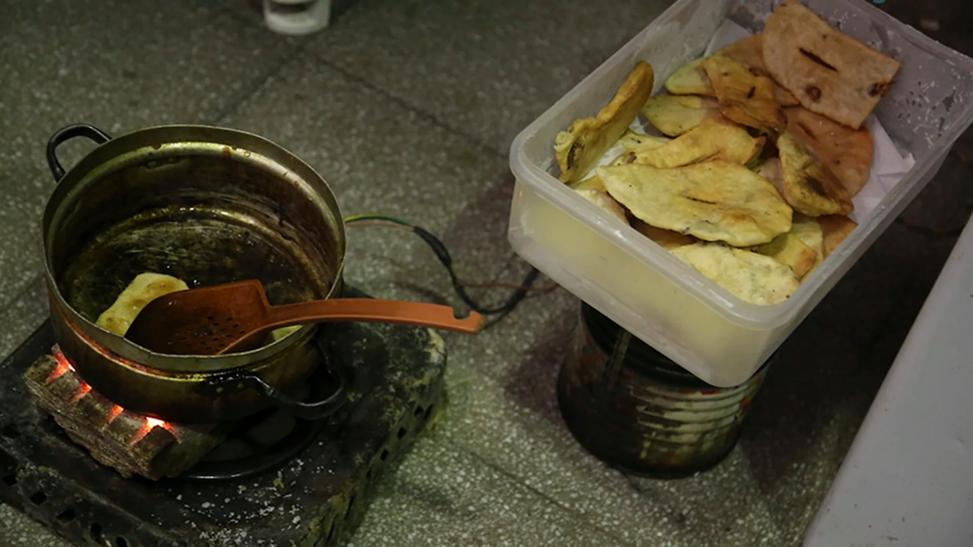 Un detenido improvisa unas batatas fritas en un brasero.