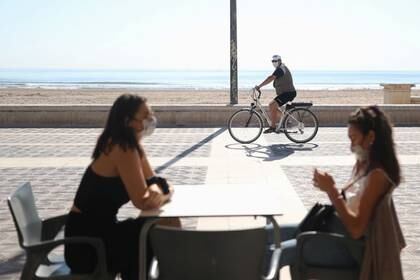 Dos mujeres con mascarillas hablan en la terraza de un restaurante en la playa de la Malvarrosa, en Valencia, España. 18 mayo 2020. REUTERS/Nacho Doce