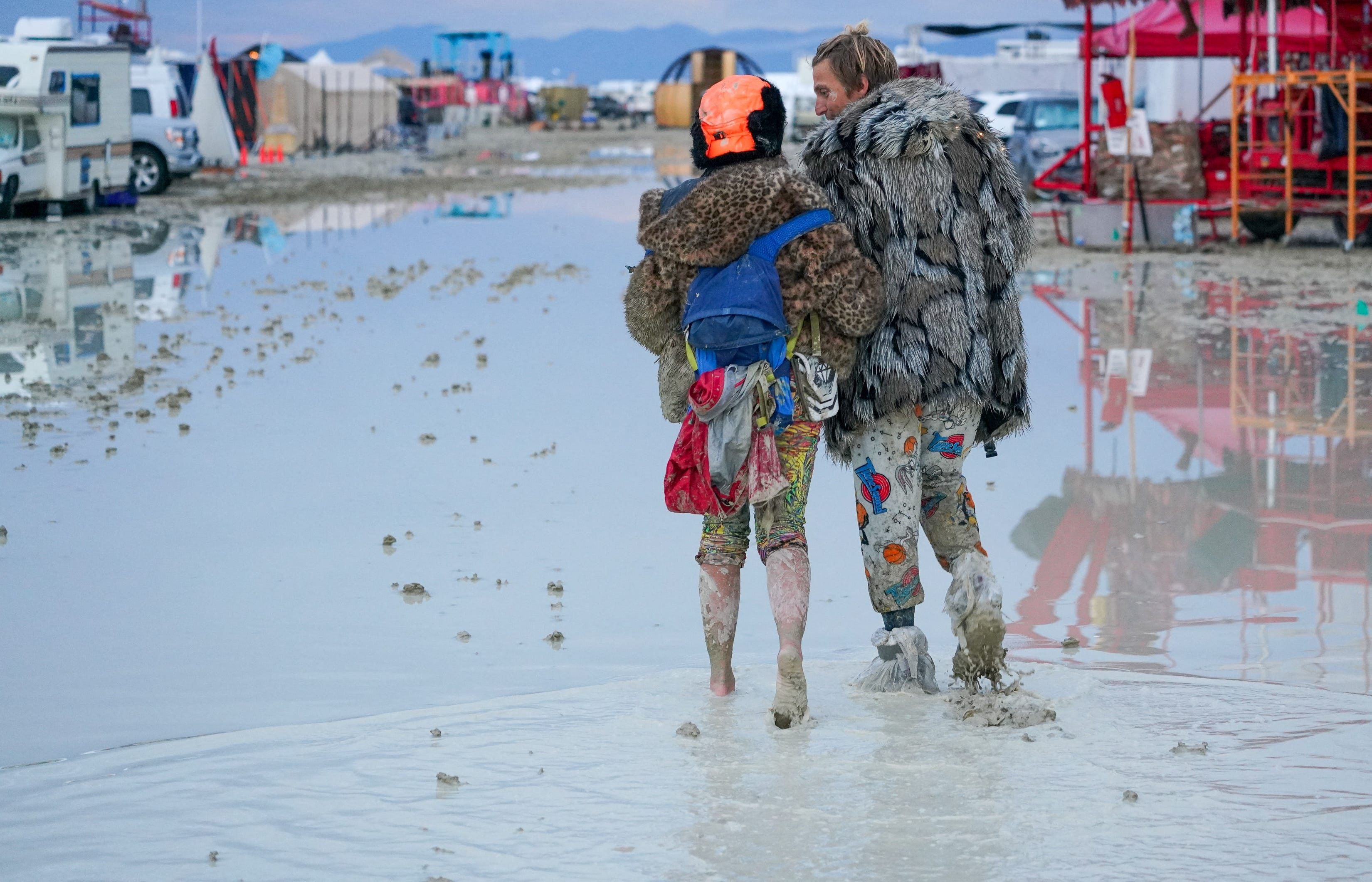 Dub Kitty y Ben Joos, de Idaho y Nevada, caminan por el barro en Burning Man después de una noche de baile con amigos en Black Rock City, en el desierto de Nevada, después de que una tormenta de lluvia convirtiera el lugar en barro el 2 de septiembre de 2023