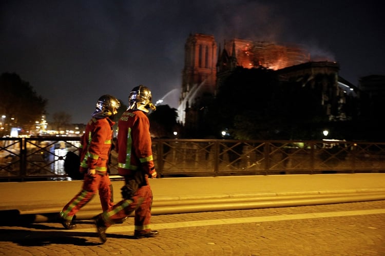 Dos bomberos caminan hacia el lugar del siniestro (Photo by GEOFFROY VAN DER HASSELT / AFP)