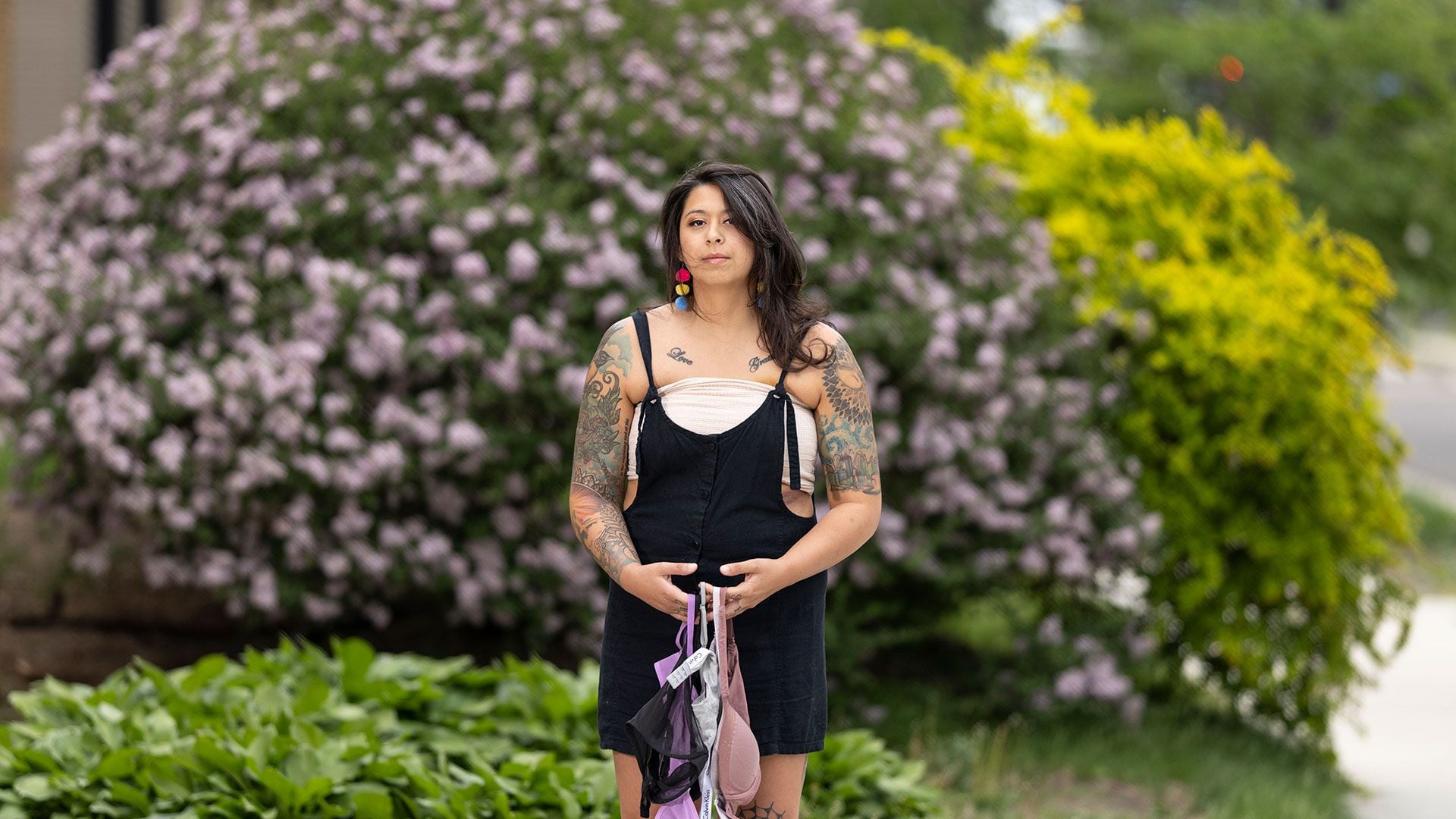 Lindsey Madla, con un vendaje de su cirugía por su cáncer de mama, sostiene sostenes que ya no necesita (Jenn Ackerman para The Washington Post)
