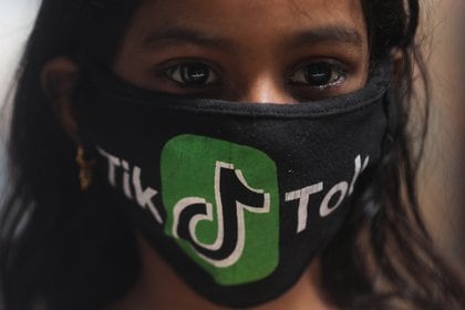 Una joven usa una mascarilla con el logo de TikTok en una barriada de Mumbai (Reuters)