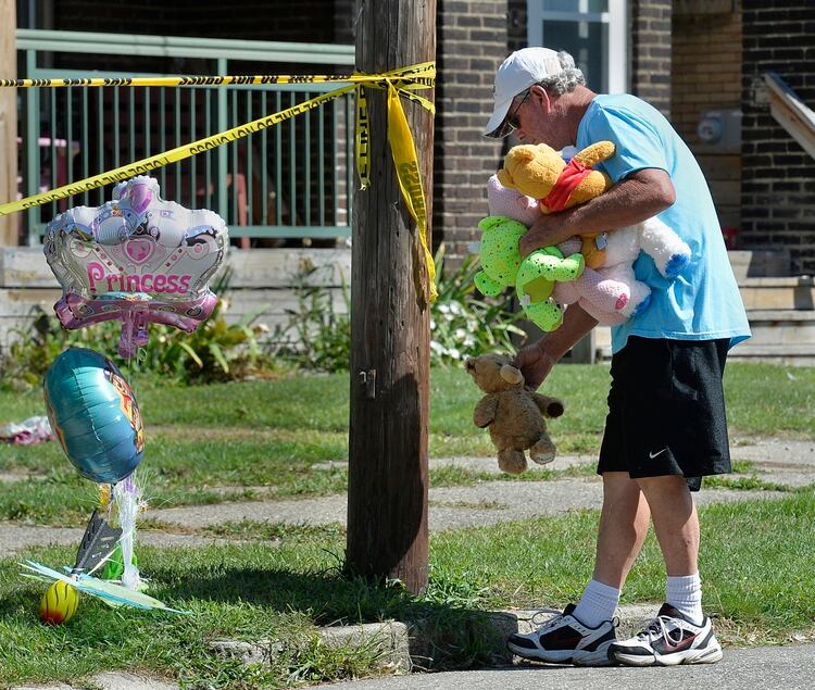 Paul Laughlin, de 57 años, coloca animales de peluche afuera de una casa en Erie, Pensilvania, donde varios niños murieron (AP)