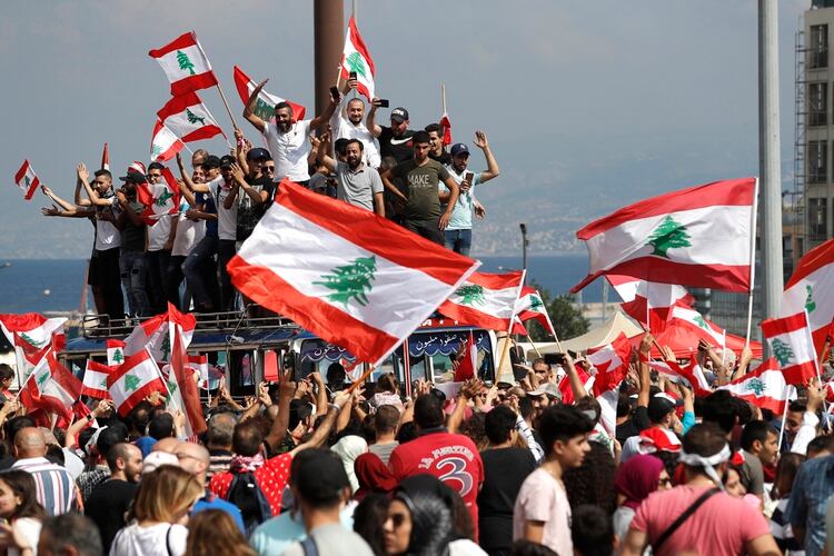 Manifestantes en contra del gobierno gritan consignas y ondean banderas en el centro de Beirut, el domingo 20 de octubre de 2019. (AP Foto/Hussein Malla)