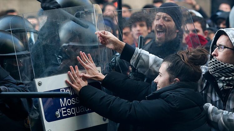 Los miembros de la policía regional catalana Mossos d’Esquadra intentan mantener a los manifestantes detrás de las barricadas de control (AFP)