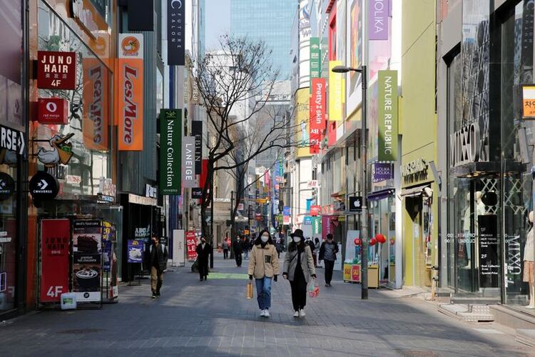 Mujeres con mascarillas de protección caminan por las calles de la capital surcoreana durante el brote del nuevo coronavirus en Seúl, Corea del Sur, el 23 de marzo de 2020. REUTERS/Heo Ran