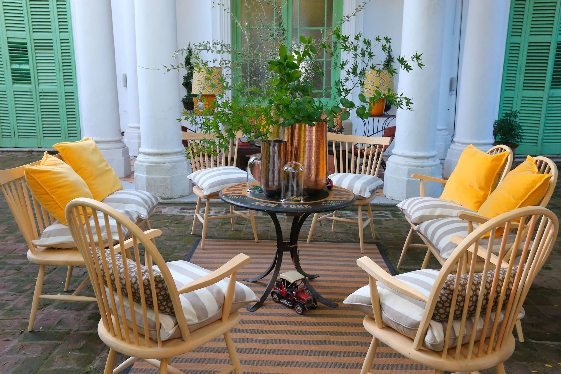Una mesa para eventos al aire libre, sillas de madera y jarrones en aluminio