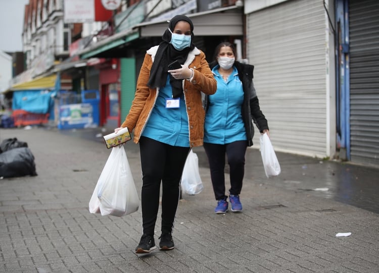 Mujeres caminan por la calle con mascarillas tras hacer las compras en Sparkhill, Reino Unido