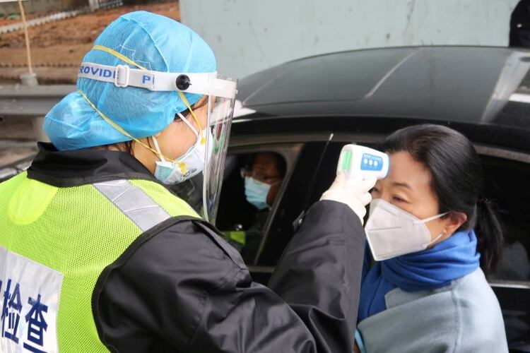 Un oficial de seguridad con una máscara protectora verifica la temperatura de un pasajero tras el brote de un nuevo coronavirus en un peaje en vísperas de las celebraciones por el Año Nuevo Lunar chino, en Xianning, provincia de Hubei (REUTERS/Martin Pollard)
