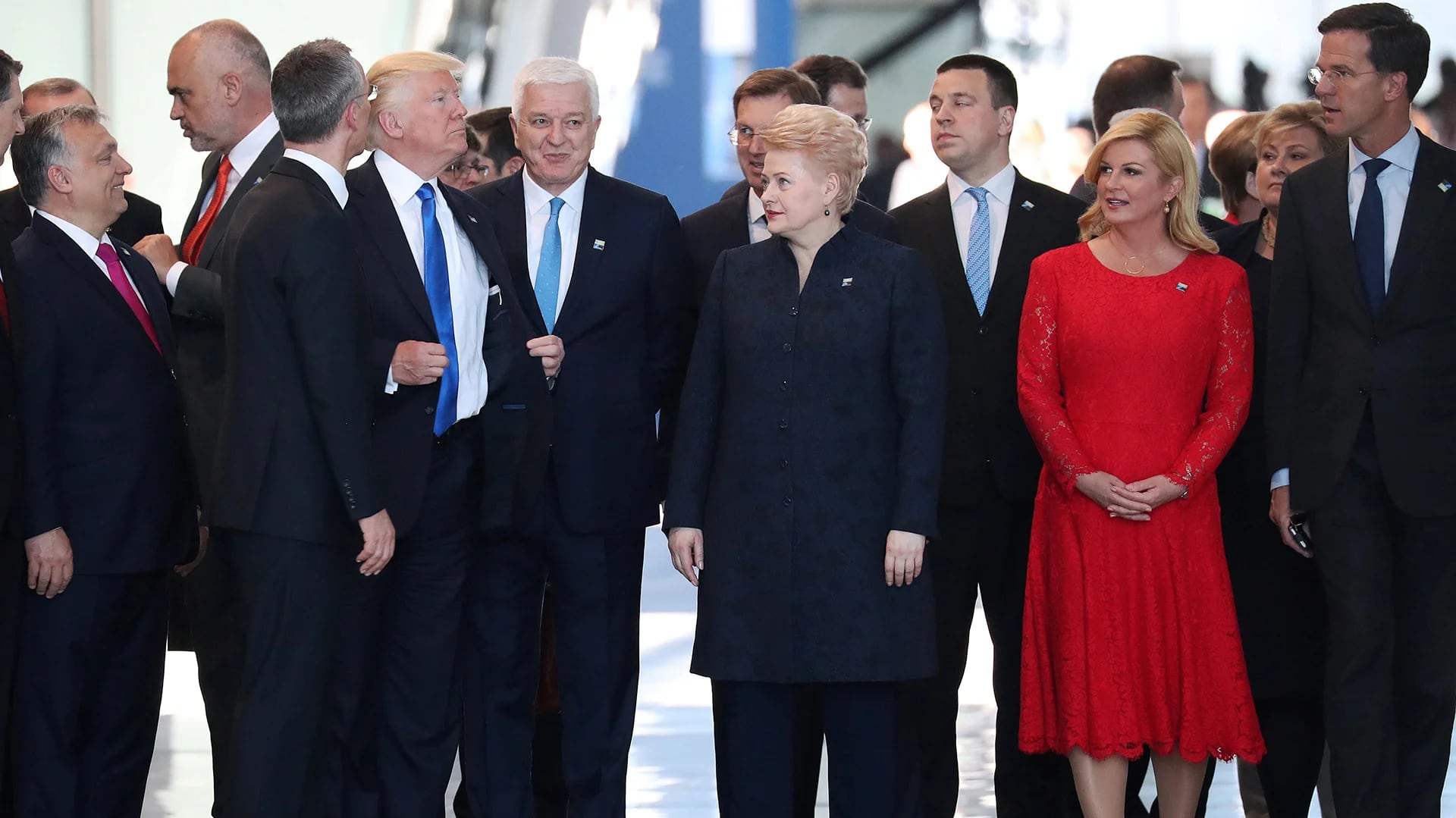 En un gesto de autoridad, el presidente de Estados Unidos acomoda su traje luego de empujar al primer ministro de Montenegro para ocupar su puesto en la foto familiar de la alianza (Reuters)