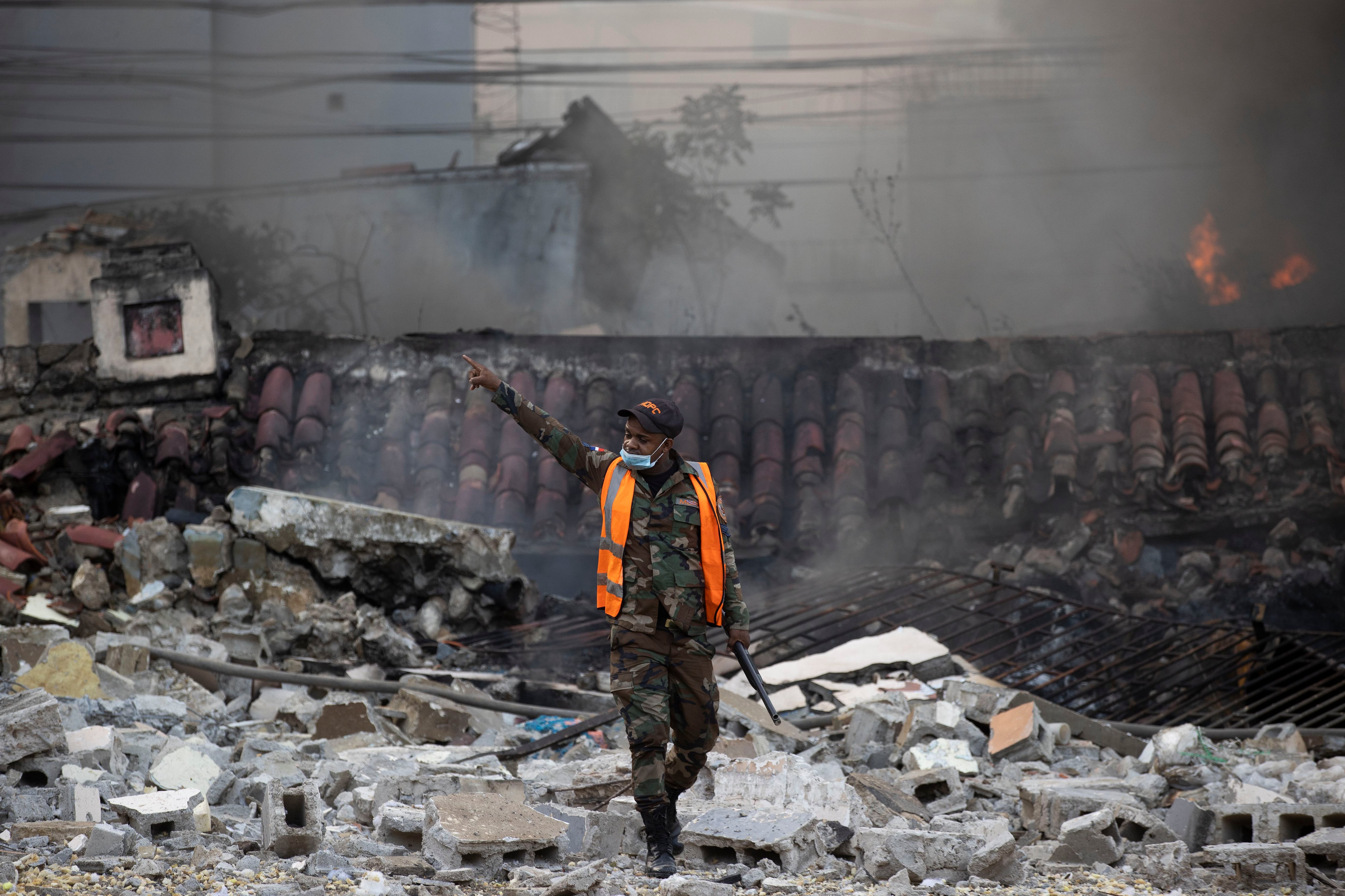 Un integrante del ejército dominicano señala para alejar a personas de los locales afectados por una explosión en San Cristóbal (República Dominicana). . EFE/ Orlando Barría
