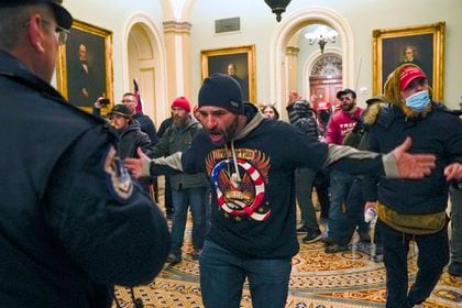 Partidarios de Trump se enfrentan a la policía del Capitolio en el pasillo fuera de la cámara del Senado (AP Photo/Manuel Balce Ceneta)