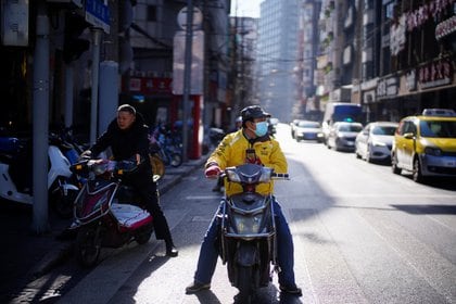 Un trabajador de reparto de Meituan con una mascarilla en una calle de Shanghai, China. Las condiciones de trabajo a las que son sometidos violan normativas nacionales e internacionales sin que las autoridades intervengan (Reuters)