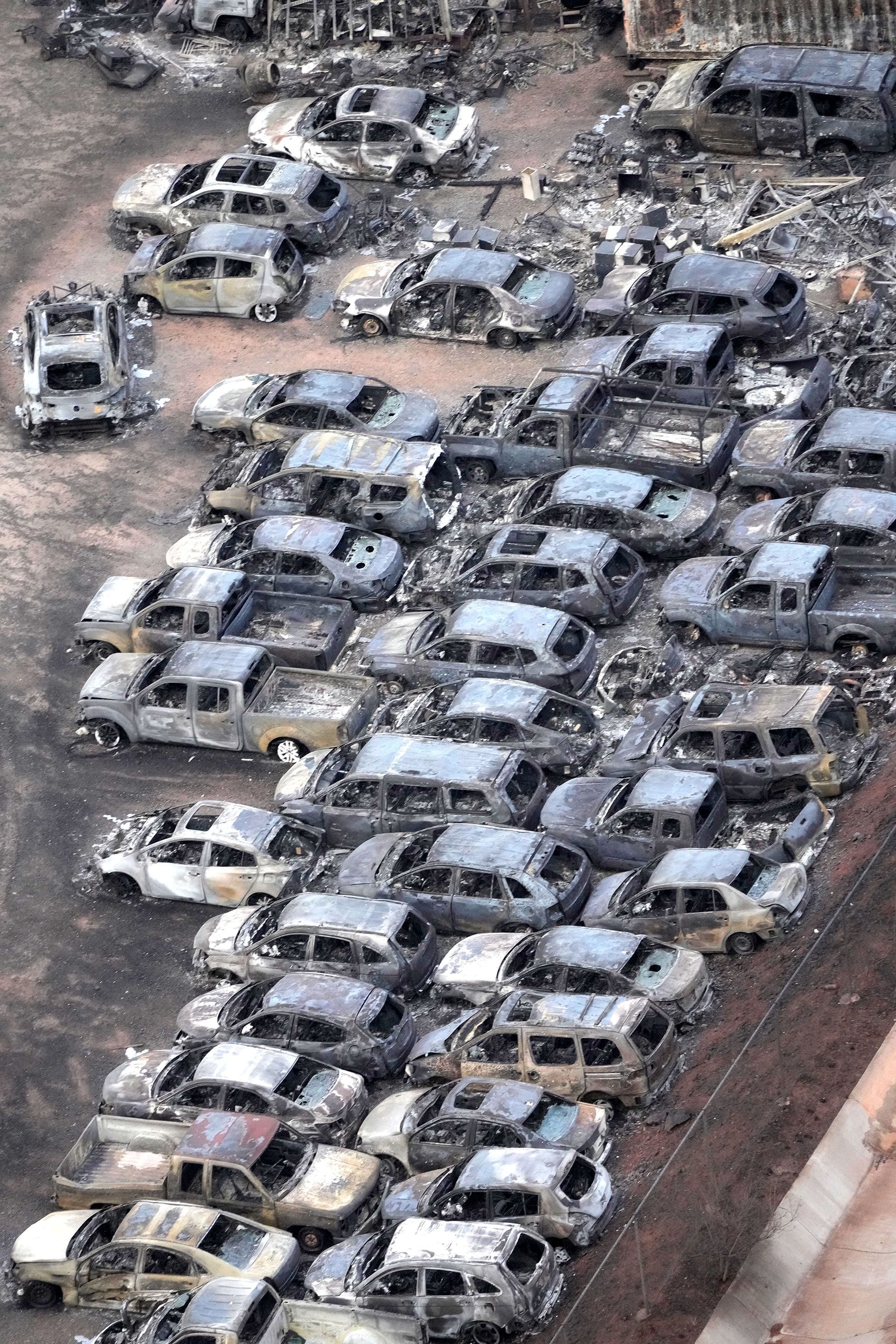 Imagen general de un gran número de autos incendiados en un estacionamiento.
