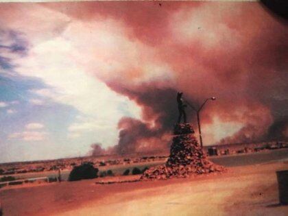 Un ícono de Puerto Madryn: el monumento al Indio Tehuelche y de fondo, el humo y las llamas del trágico 21 de enero de 1994