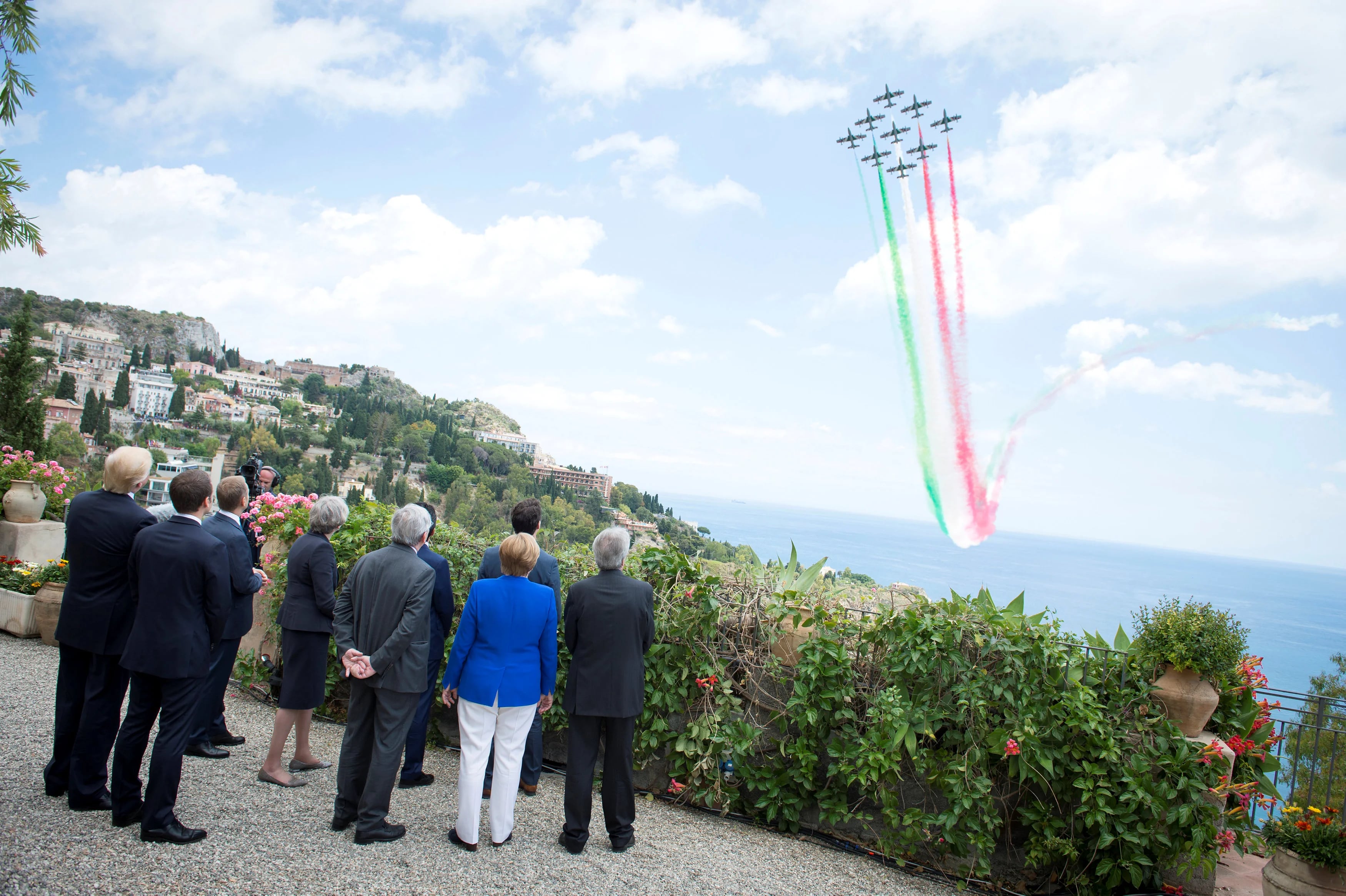 Líderes del G7 osbveran a un escuadrón de la fuerza aérea italiana desplegar una bandera italiana por los aires.