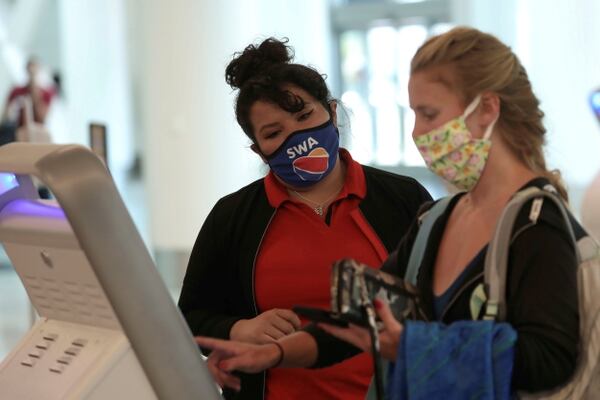 FILE PHOTO: A Southwest Airlines Co. employee wears a protective mask while assisting a passenger at Los Angeles International Airport (LAX) in Los Angeles, California, U.S., May 23, 2020. REUTERS/Patrick T. Fallon -/File Photo