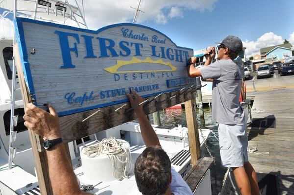 Los hombres quitan el cartel de su barco ante la llegada del huracán (Devon Ravine/Northwest Florida Daily News via AP)