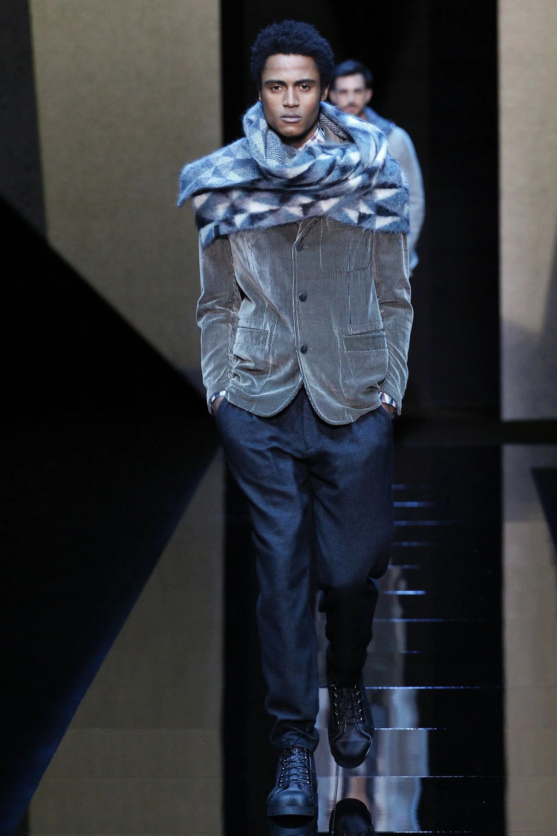 El saco de corderoy es uno de los clásicos en los vestidores de los hombres. Armani lo desfiló en cemento acompañado con un pantalón de vestir y una maxi bufanda geométrica.