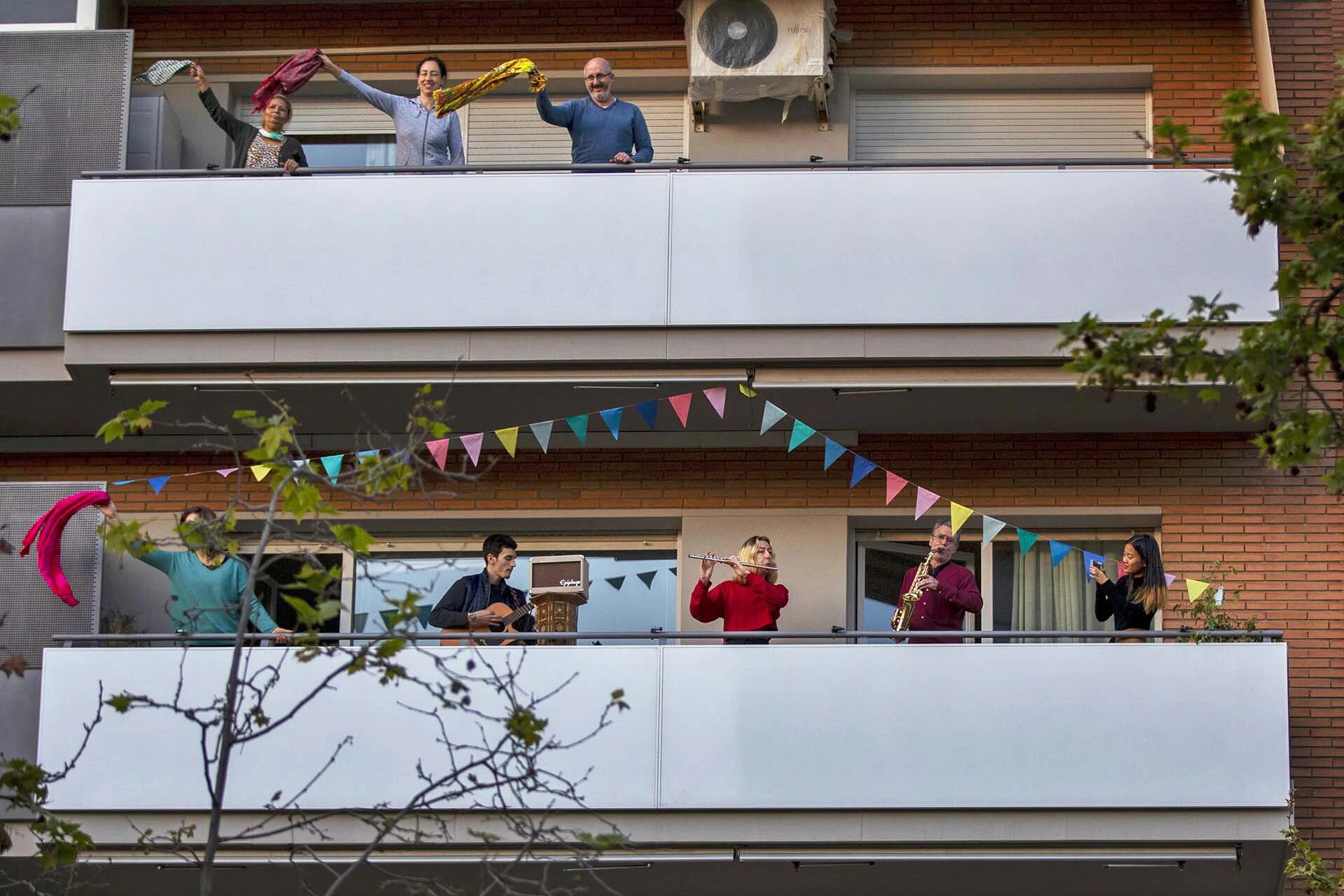 Vecinos hacen música mientras otro grupo baila en sus balcones en apoyo al personal médico en Barcelona, España (AP Photo/Emilio Morenatti, File)