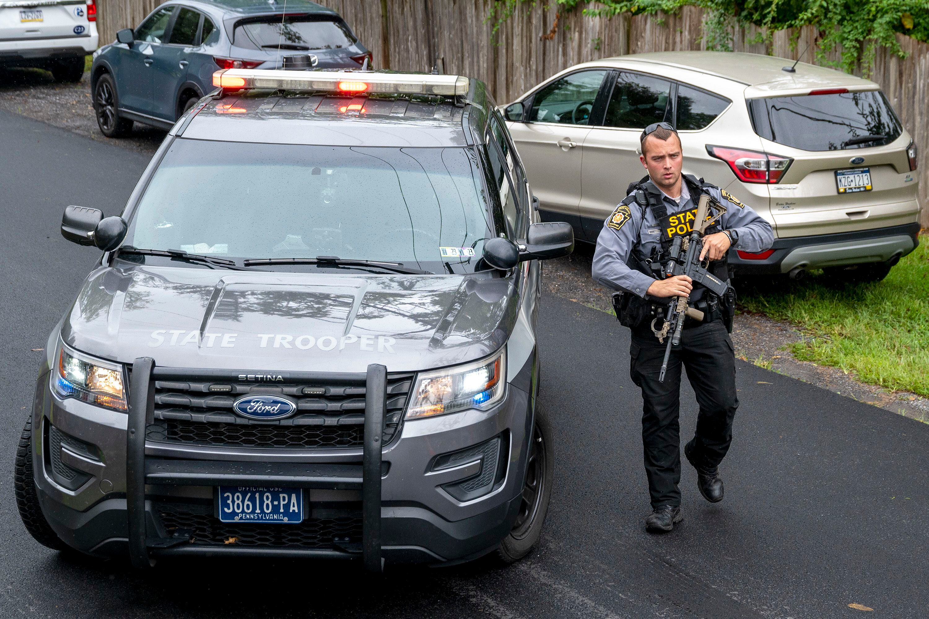 Un policía estatal de Pensilvania y otros oficiales buscan en Nantmeal Village a Danelo Cavalcante  (Tom Gralish/The Philadelphia Inquirer vía AP)