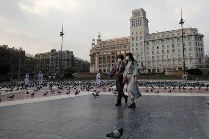 Mujeres usando mascarillas mientras caminan por una vacía Plaça de Catalunya, en medio de las preocupaciones por la pandemia del coronavirus, en Barcelona, España (REUTERS/Nacho Doce/Archivo)