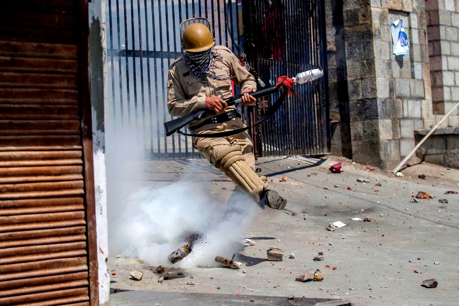 Un policía indio patea un proyectil de gas lacrimógeno en un intento de arrojarlo hacia los manifestantes en Srinagar, en el valle de Cachemira, controlado por la India