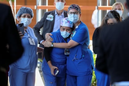 Nurse Alyssa Brown (R) hugs fellow nurse Rosa Arana-Santiago as they celebrate the release of a COVID-19 patient after 45 days in their care  during the outbreak of the coronavirus disease (COVID-19) in Orange, California, U.S., May 5, 2020.      REUTERS/Mike Blake