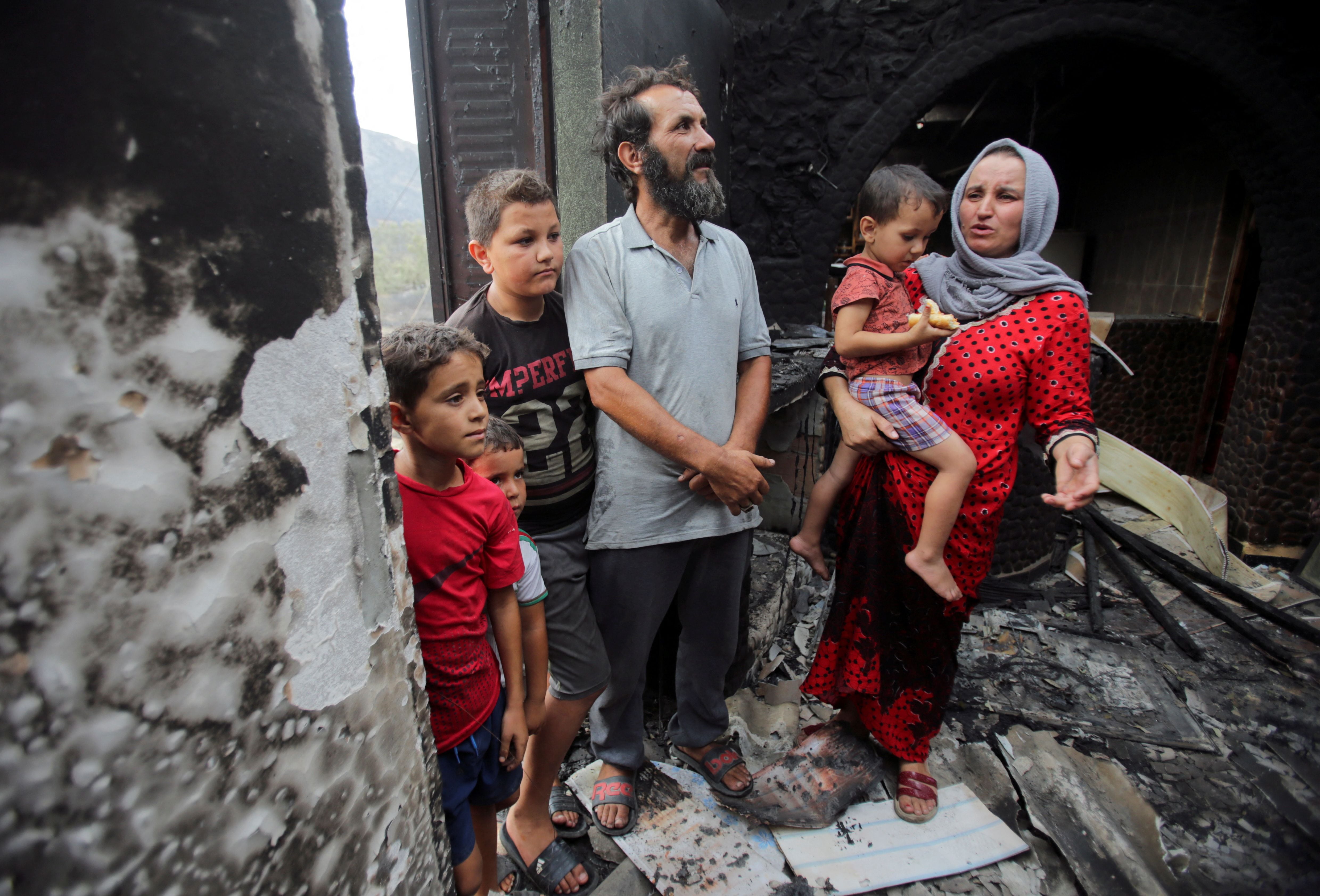 Amar Belkati, un agricultor de 57 años, junto a su esposa Souhila y sus hijos en el interior de su casa quemada en Bejaia (REUTERS/Ramzi Boudina)