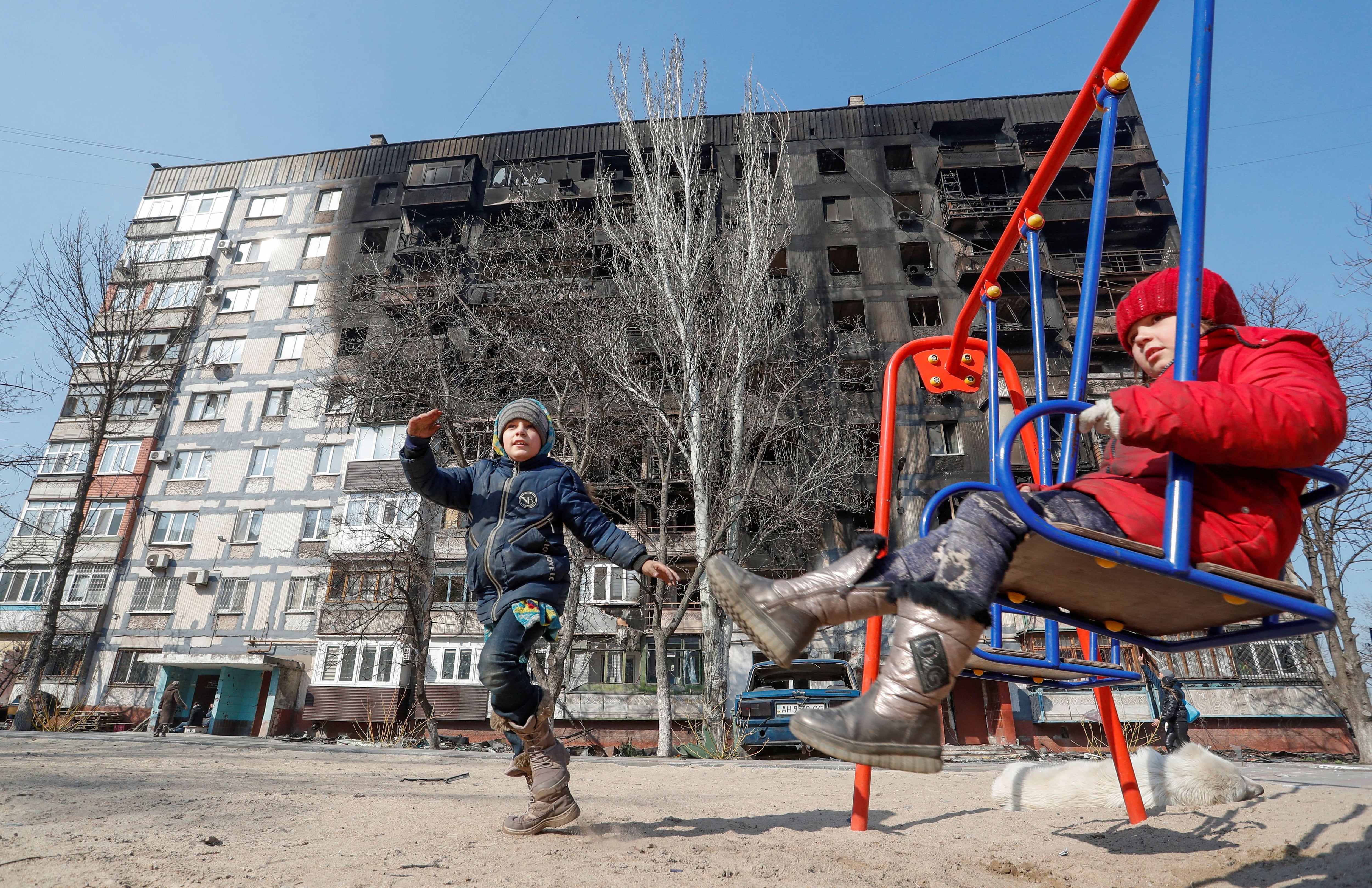 Los niños juegan frente a un edificio dañado en los combates en Mariupol, Ucrania, el 23 de marzo de 2022. (REUTERS/Alexander Ermochenko)