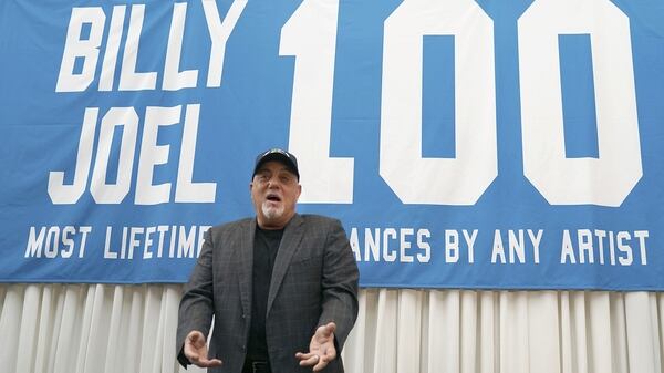 Billy Joel junto a la banderola celebrando la actuación 100 (AFP)